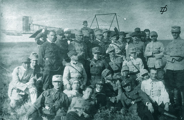 Un grup de ofiteri-elevi piloti in fata trainerului „Pinguin”; in mijlocul grupului slt. Raducanescu S. Nicolae, marcat cu o bulina pe buzunarul din dreapta al vestonului. Tecuci, 1921