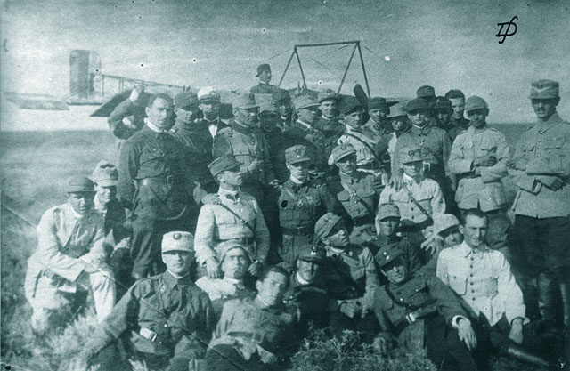 Un grup de ofiteri-elevi piloti in fata trainerului Pinguin; in mijlocul grupului slt. Raducanescu S. Nicolae, marcat cu o bulina pe buzunarul din dreapta al vestonului. Tecuci, 1921